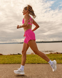 Woman wearing Accelerate 3" Pleated Running Short - Ultra Pink | Model:Phoebe | Size:M