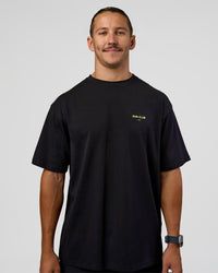 Man wearing RUN CLUB FLXCotton Tee Oversize - Black-Yellow Fizz | Model:Jaiden | Size:M