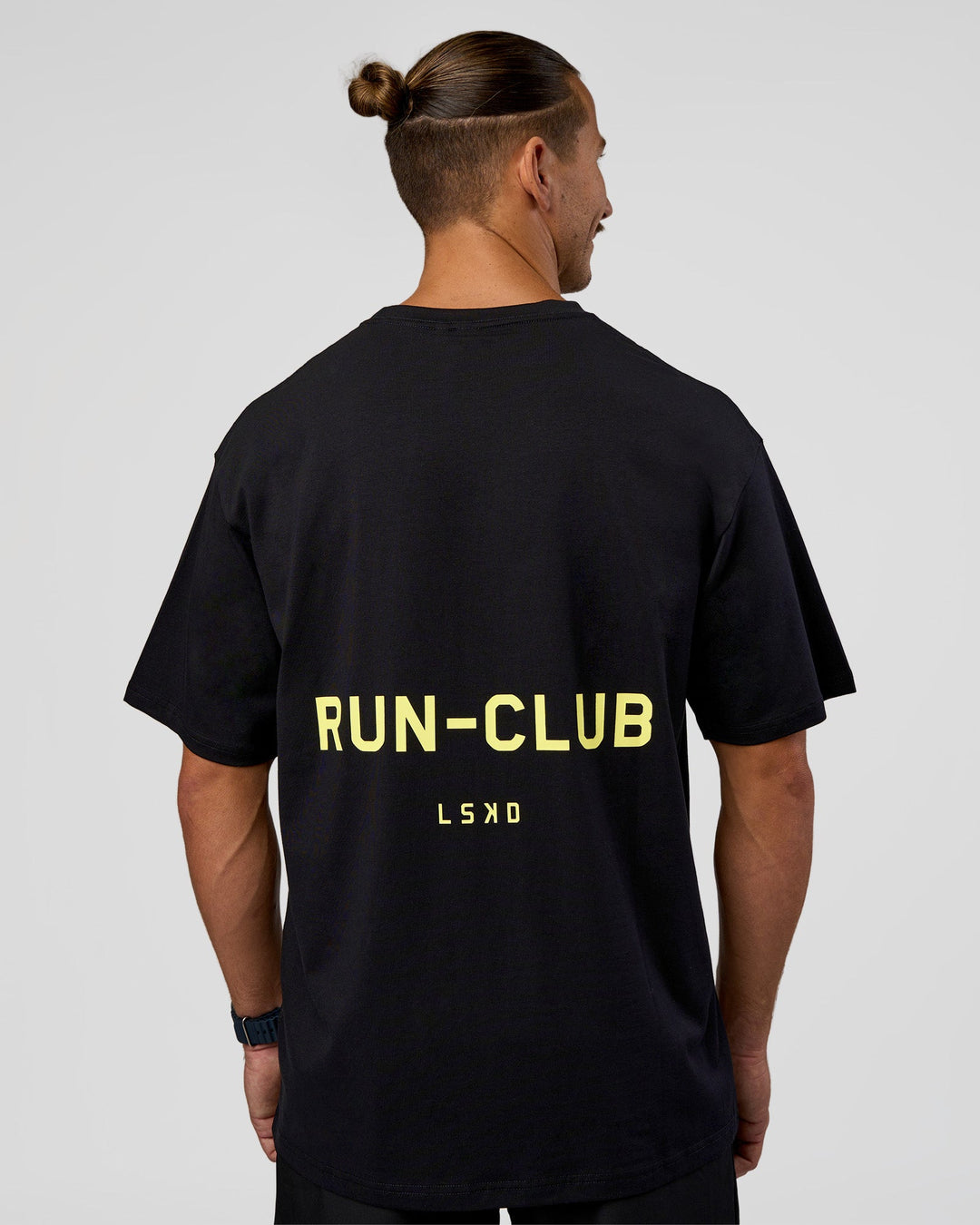 Man wearing RUN CLUB FLXCotton Tee Oversize - Black-Yellow Fizz | Model:Jaiden | Size:M