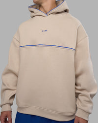 Man wearing Unisex Oversized Piping Hoodie - Shale Beige-Power Cobalt | Model:Jaiden | Size:M