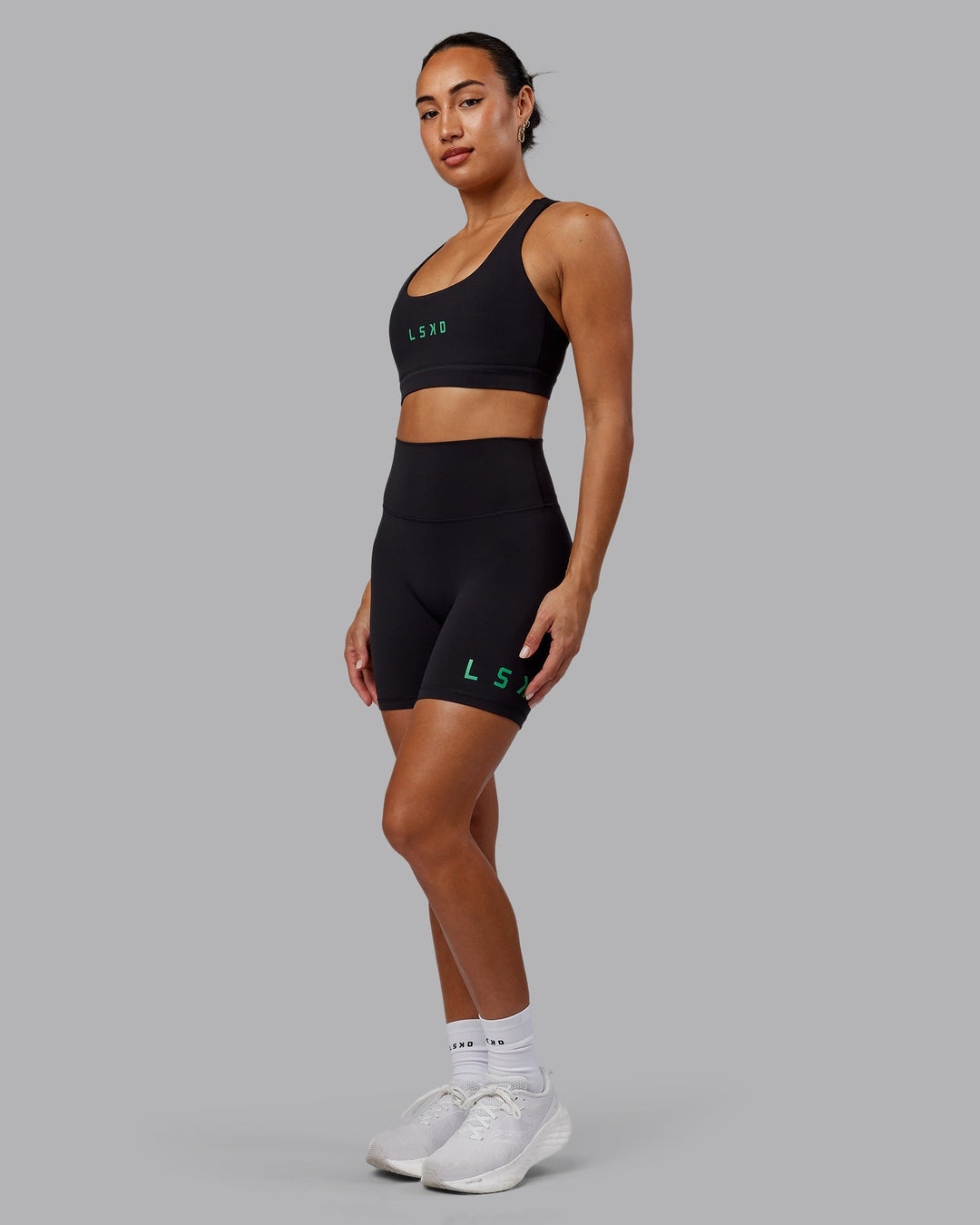 Woman wearing Evolved Mid-Length Shorts - Black-Impact Green