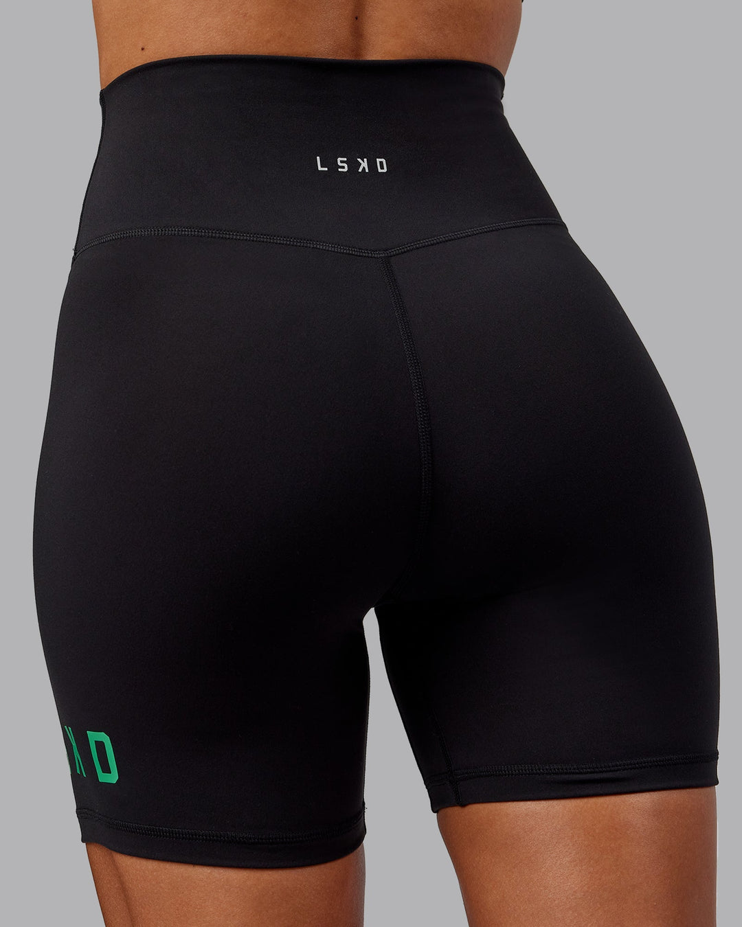 Woman wearing Evolved Mid-Length Shorts - Black-Impact Green