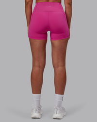 Woman wearing Fusion Ultra High-Rise 4" Short Pockets - Fuchsia Pink | Set:true | Angle:back | Model:Sophie | Size:S