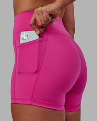 Woman wearing Fusion Ultra High-Rise 4" Short Pockets - Fuchsia Pink | Set:true | Angle:closeup | Model:Sophie | Size:S