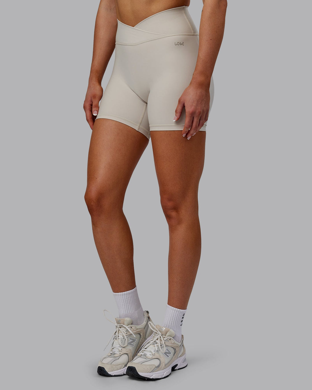 Woman wearing Sara Strike Cross Over Waist Mid-Length Shorts - Shale Beige