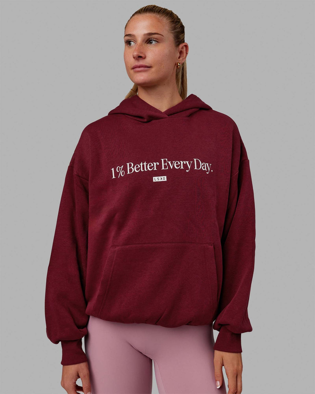 Woman wearing Unisex 1% Better Hoodie Oversize - Cranberry-White