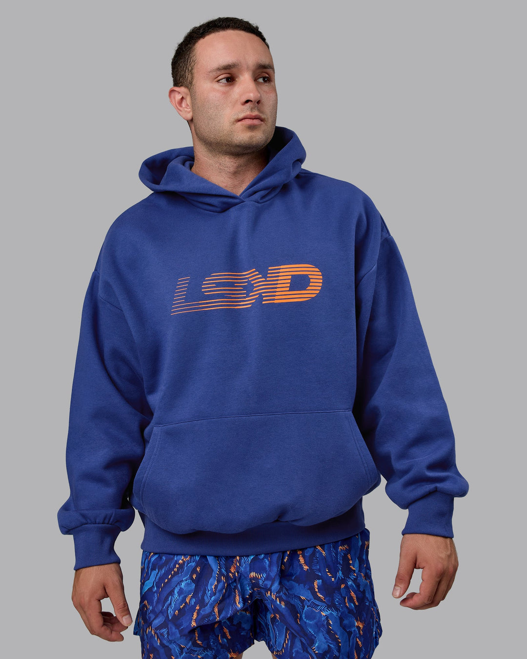 Man wearing Unisex Motion Hoodie Oversize - Galactic Cobalt-Vibrant Orange