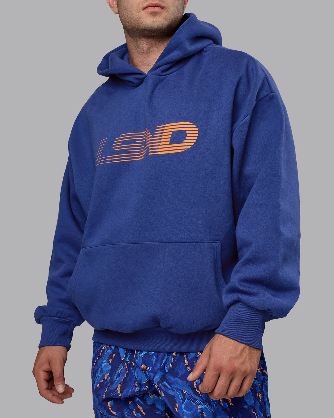 Man wearing Unisex Motion Hoodie Oversize - Galactic Cobalt-Vibrant Orange