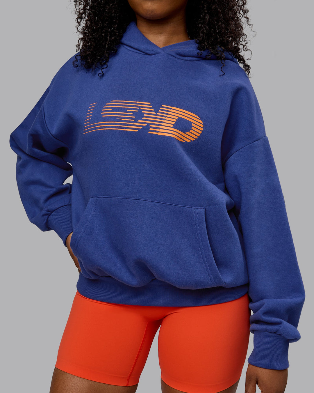 Woman wearing Unisex Motion Hoodie Oversize - Galactic Cobalt-Vibrant Orange