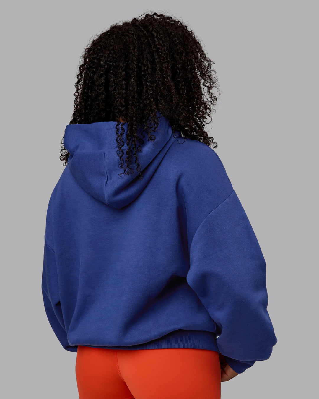 Woman wearing Unisex Motion Hoodie Oversize - Galactic Cobalt-Vibrant Orange