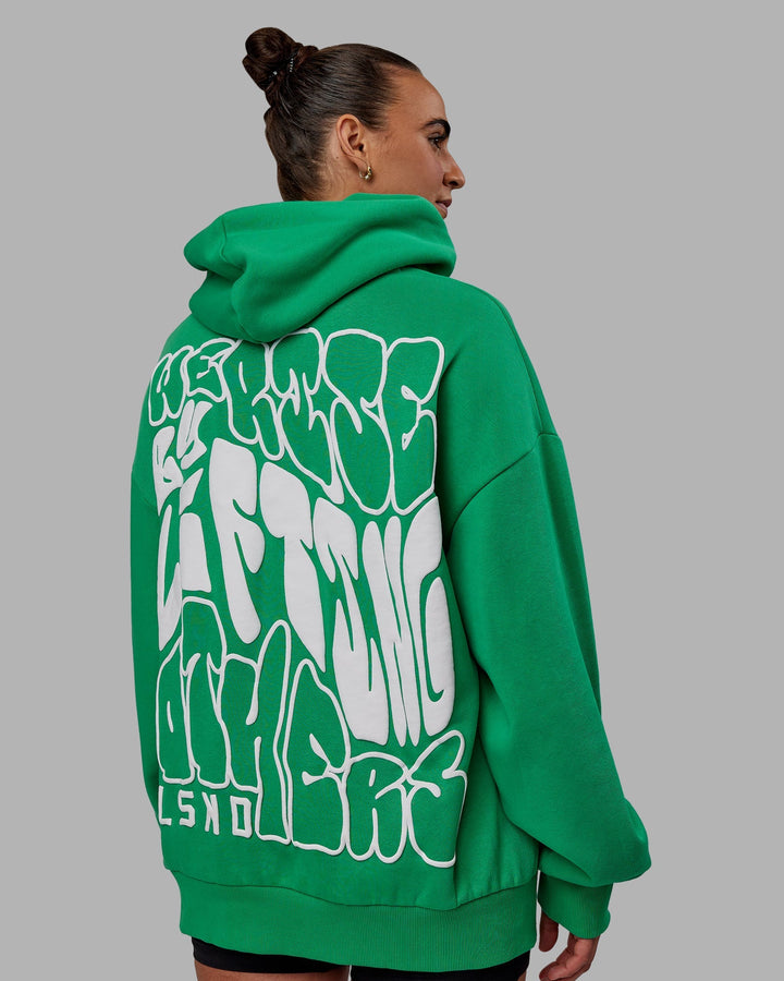 Woman wearing Unisex We Rise Hoodie Oversize - Impact Green-White
