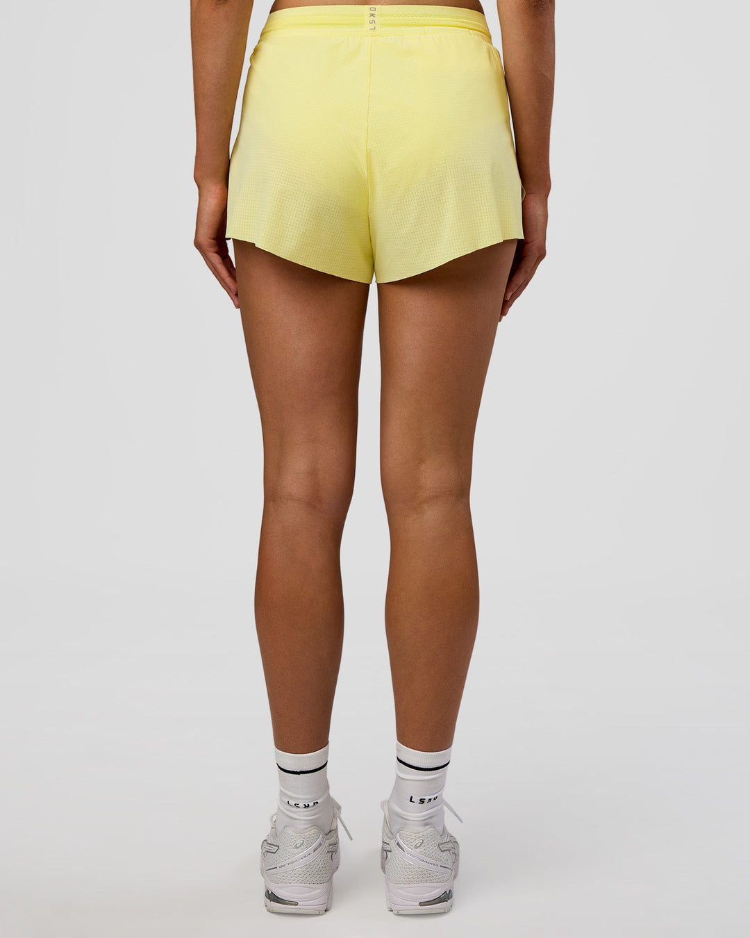 Woman wearing Accelerate 3" High-Rise Running Short - Yellow Fizz | Set:true | Angle:back | Model:Evie | Size:S