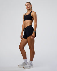 Woman wearing Accelerate 3" Pleated Mid-Rise Running Short - Black | Model:Emelia | Size:S