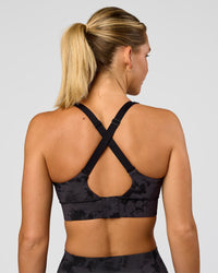 Woman wearing Accelerate Sports Bra - Black Tie Dye | Set:true | Angle:back | Model:Amity | Size:S