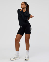 Woman wearing Elite Hype Reflective Run High-Rise 7" Short Pockets - Black-Hype Reflective | Model:Sophia | Size:S