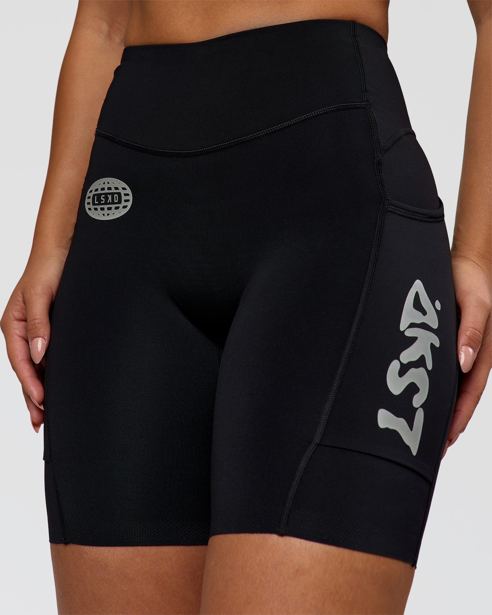 Woman wearing Elite Hype Reflective Run High-Rise 7" Short Pockets - Black-Hype Reflective | Model:Sophia | Size:S