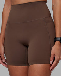 Woman wearing Elixir Ultra High-Rise 6" Short Pockets - Chocolate Martini | Model:Rhiley | Size:S