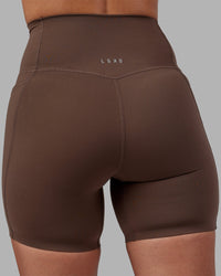 Woman wearing Elixir Ultra High-Rise 6" Short Pockets - Chocolate Martini | Model:Rhiley | Size:S