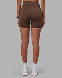 Woman wearing Elixir Ultra High-Rise 6" Short Pockets - Chocolate Martini | Model:Rhiley | Size:S