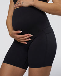 Woman wearing Elixir Ultra High-Rise Maternity 6" Short Pockets - Black | Model:Kitahna | Size:S