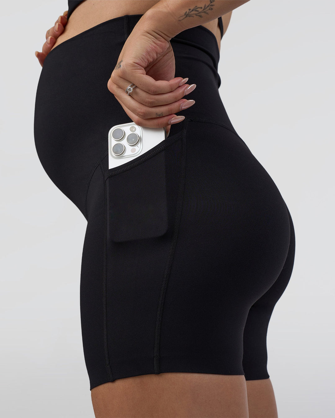 Woman wearing Elixir Ultra High-Rise Maternity 6&quot; Short Pockets - Black | Model:Kitahna | Size:S