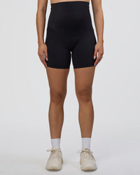 Woman wearing Elixir Ultra High-Rise Maternity 6" Short Pockets - Black | Model:Kitahna | Size:S