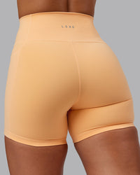 Woman wearing Fusion Ultra High-Rise 6" Short Pockets - Peach Fuzz | Model:Lyss | Size:S