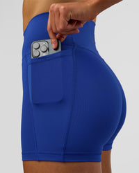 Woman wearing Fusion Ultra High-Rise 4" Short Pockets - Electric Indigo | Model:Evie | Size:S