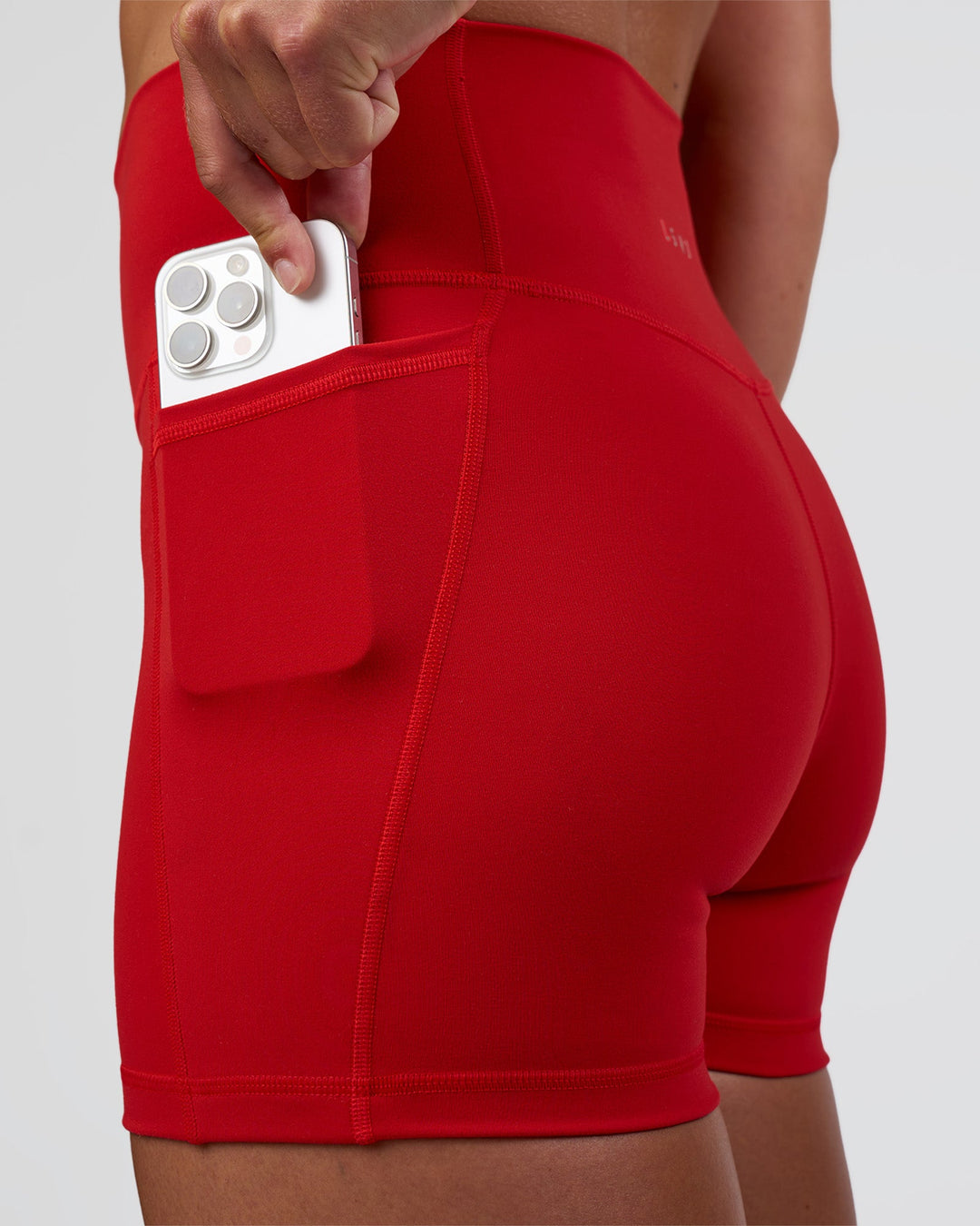 Woman wearing Fusion Ultra High-Rise 4" Short Pockets - Flame | Set:true | Angle:closeup | Model:Sav | Size:S