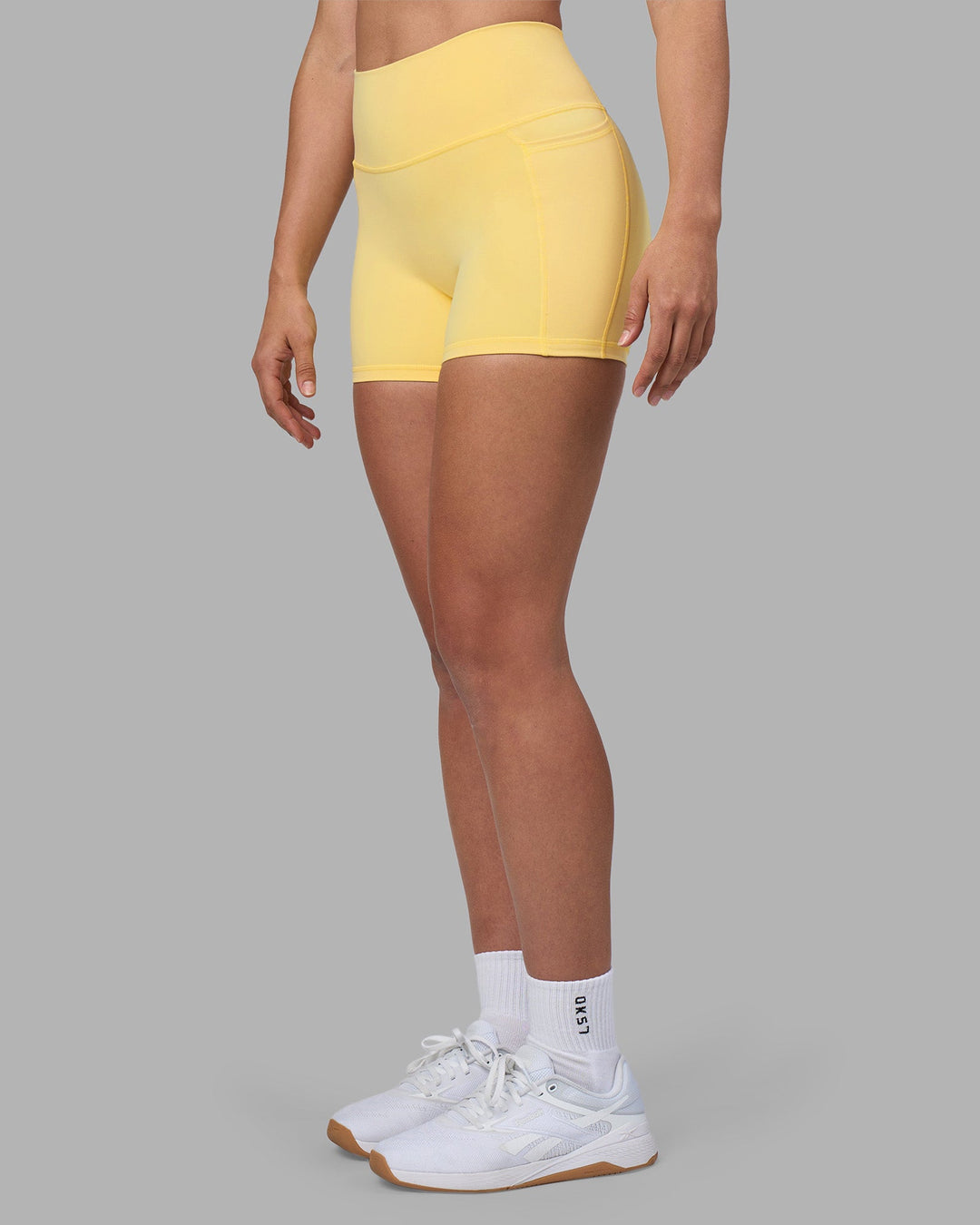 Woman wearing Fusion Ultra High-Rise 4" Short Pockets - Lemon | Set:true | Angle:side | Model:Sophie | Size:S