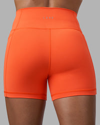 Woman wearing Fusion Ultra High-Rise 4" Short Pockets - Ultra Orange | Model:Katie | Size:S