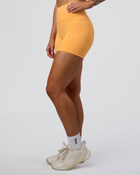Woman wearing Fusion Ultra High-Rise 4" Short Pockets - Warm Apricot | Model:Emelia | Size:S