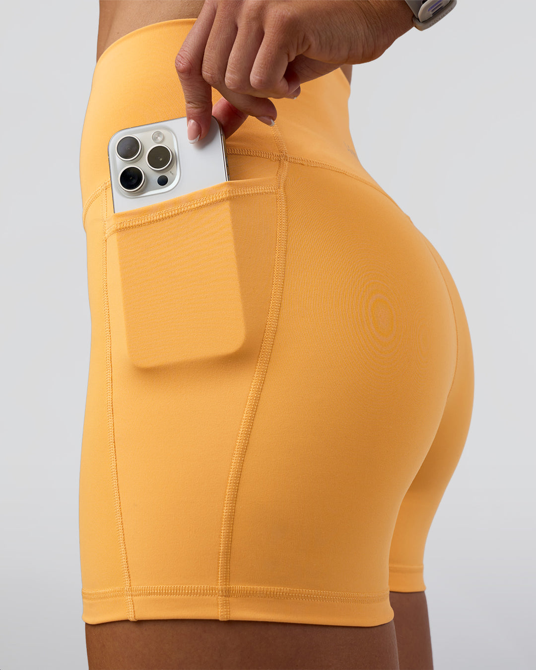 Woman wearing Fusion Ultra High-Rise 4&quot; Short Pockets - Warm Apricot | Model:Emelia | Size:S