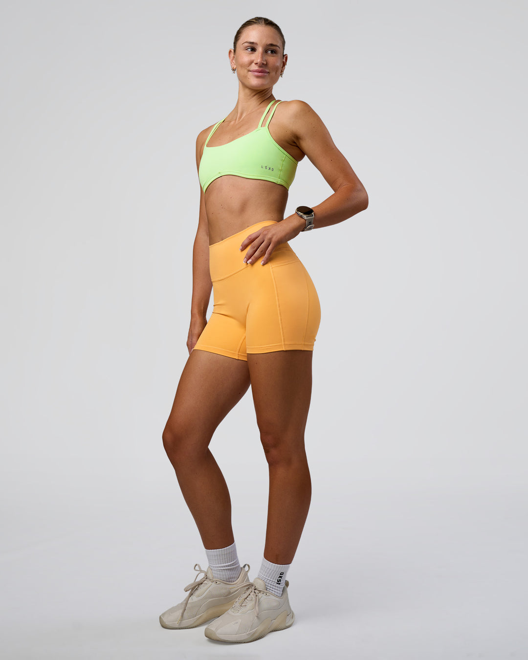 Woman wearing Fusion Ultra High-Rise 4&quot; Short Pockets - Warm Apricot | Model:Emelia | Size:S