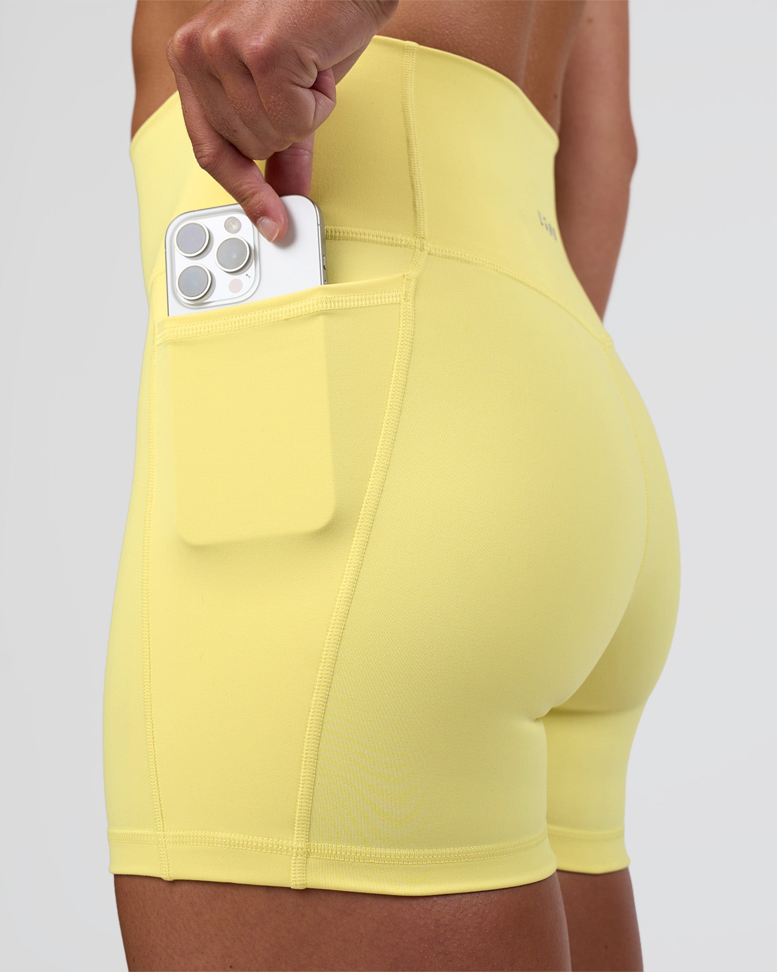 Woman wearing Fusion Ultra High-Rise 4" Short Pockets - Yellow Fizz | Model:Sav | Size:S