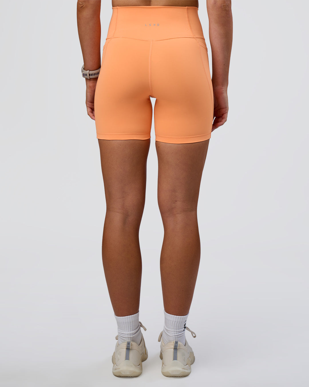 Woman wearing Fusion Ultra High-Rise 6" Short Pockets - Cantaloupe | Set:true | Angle:back | Model:Emelia | Size:S