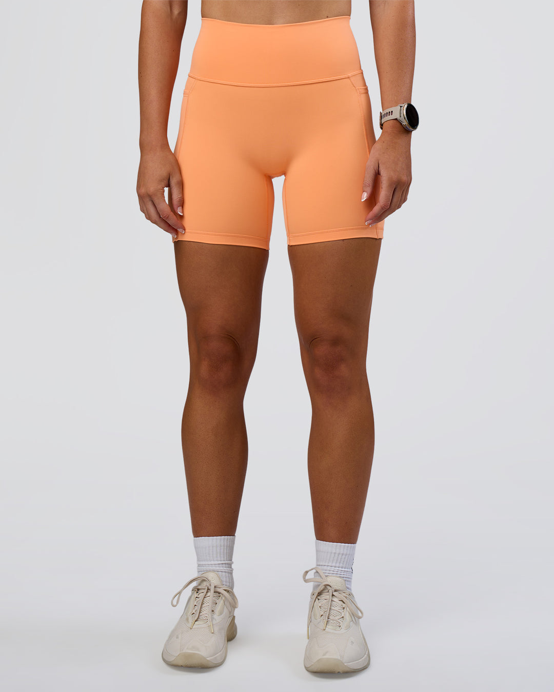 Woman wearing Fusion Ultra High-Rise 6" Short Pockets - Cantaloupe | Set:true | Angle:front | Model:Emelia | Size:S