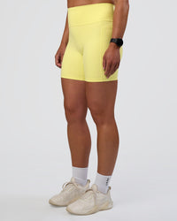 Woman wearing Fusion Ultra High-Rise 6" Short Pockets - Yellow Fizz | Set:true | Angle:side | Model:Sav | Size:S