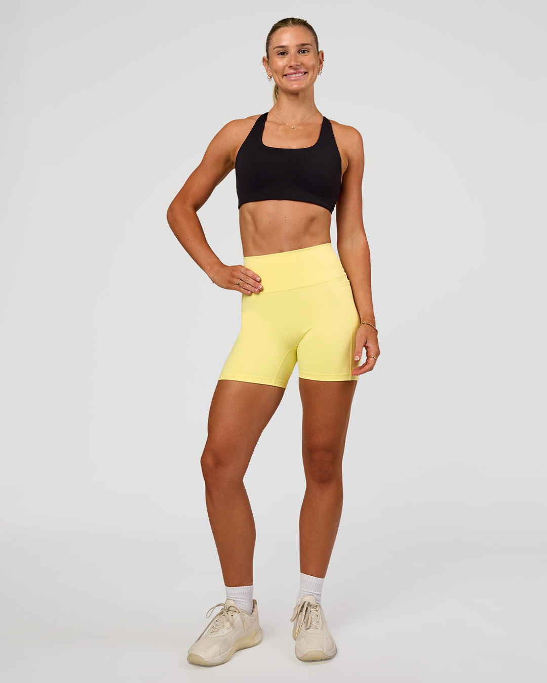 Woman wearing Fusion V-Contour Ultra High-Rise 4” Short Pockets - Yellow Fizz | Model:Emelia | Size:S