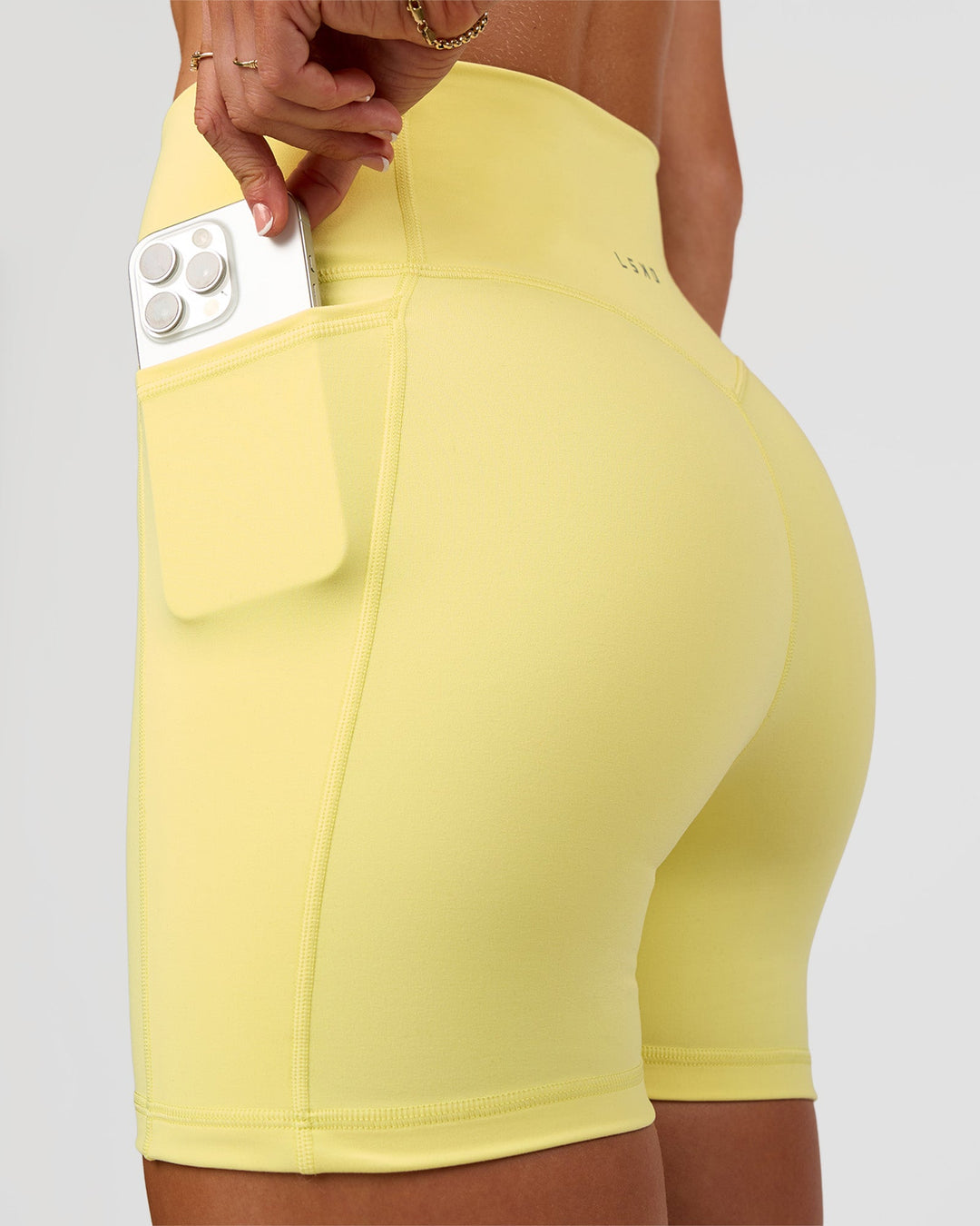 Woman wearing Fusion V-Contour Ultra High-Rise 4” Short Pockets - Yellow Fizz | Model:Emelia | Size:S
