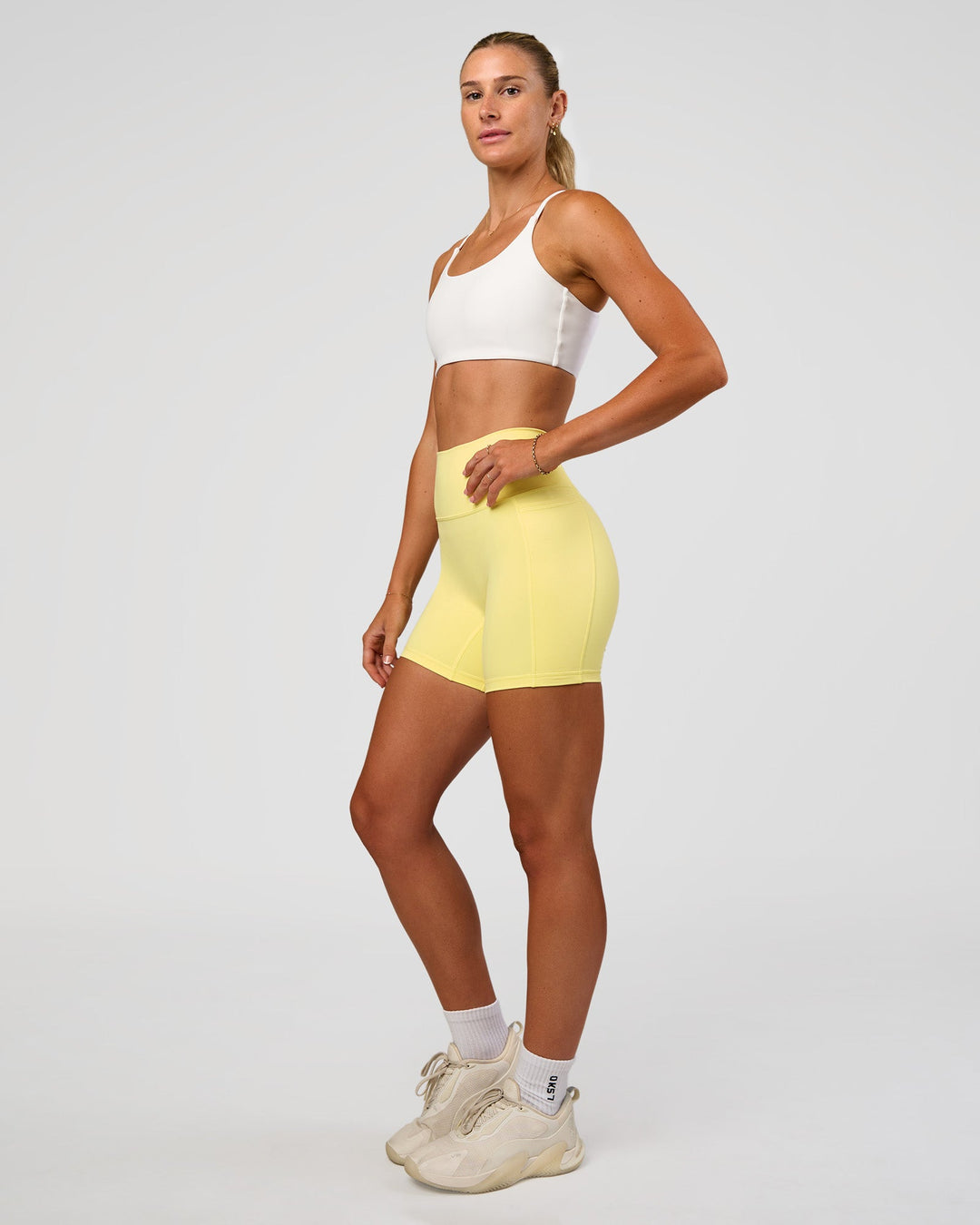 Woman wearing Fusion V-Contour Ultra High-Rise 6" Short Pockets - Yellow Fizz | Model:Emelia | Size:S