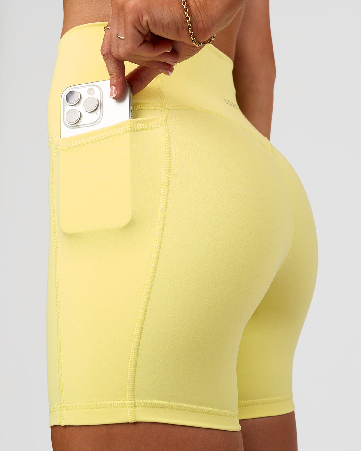 Woman wearing Fusion V-Contour Ultra High-Rise 6" Short Pockets - Yellow Fizz | Model:Emelia | Size:S