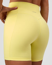 Woman wearing Fusion V-Contour Ultra High-Rise 6" Short Pockets - Yellow Fizz | Model:Emelia | Size:S