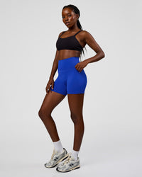 Woman wearing Fusion V-Contour Ultra High-Rise 4” Short Pockets - Electric Indigo | Model:Ellie | Size:S