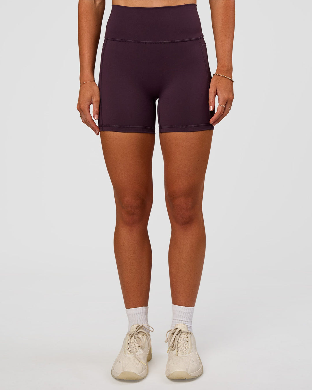 Woman wearing Fusion V-Contour Ultra High-Rise 4” Short Pockets - Midnight Plum | Model:Emelia | Size:S