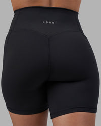 Woman wearing Fusion V-Contour Ultra High-Rise 6" Short Pockets - Black | Model:Charlize | Size:S