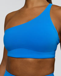 Woman wearing Muse Asymmetric Sports bra - Palace Blue | Model:Rosie | Size:S