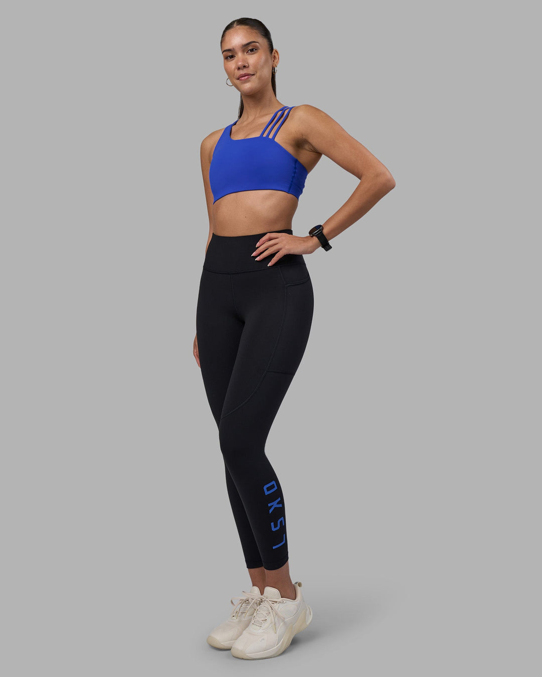 Woman wearing Rep Ultra High-Rise 7/8 Legging Pockets - Black-Power Cobalt | Model:Rhiley | Size:S