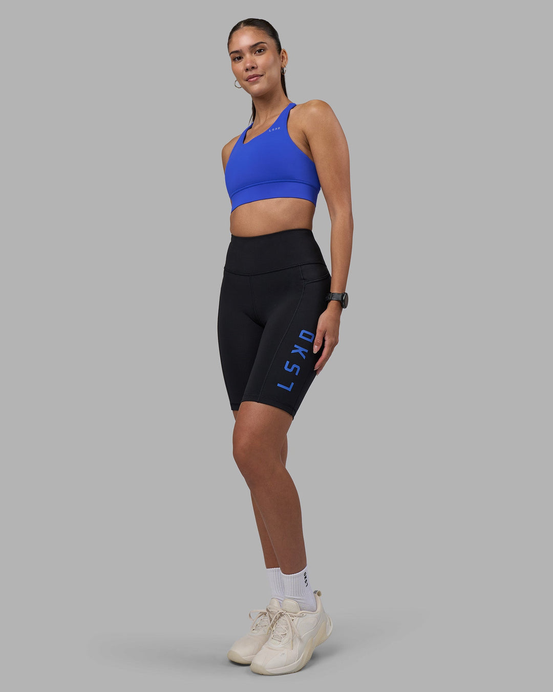 Woman wearing Rep Ultra High-Rise 9" Short Pockets - Black-Power Cobalt | Model:Rhiley | Size:S