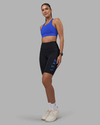 Woman wearing Rep Ultra High-Rise 9" Short Pockets - Black-Power Cobalt | Model:Rhiley | Size:S